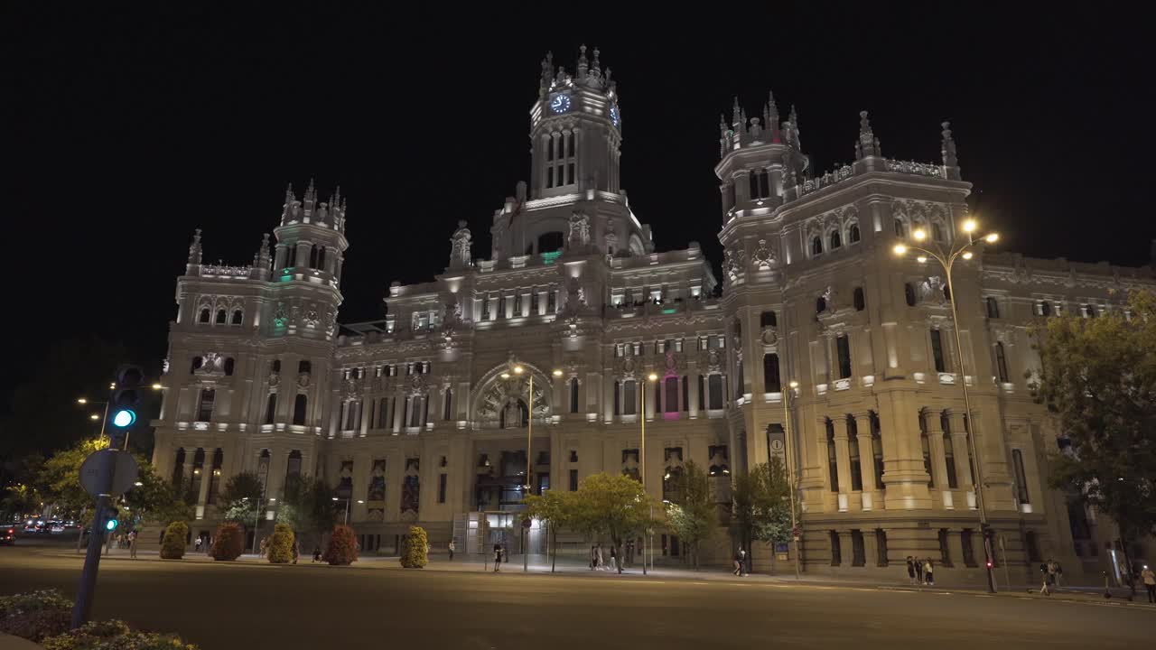 People Walk In Front Of Cybele Palace At Night In Madrid, Spain