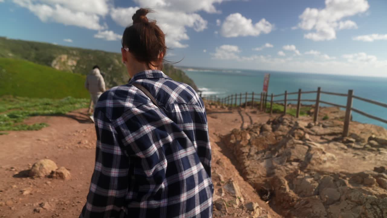 mujer caminando a lo largo del sendero costero de los acantilados