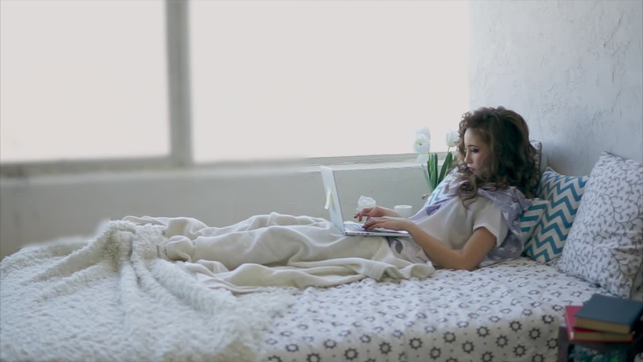 침대에서 노트북으로 일하는 여자