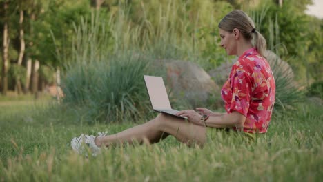 a middle-aged woman works using her laptop in a public park. she types and thinks.