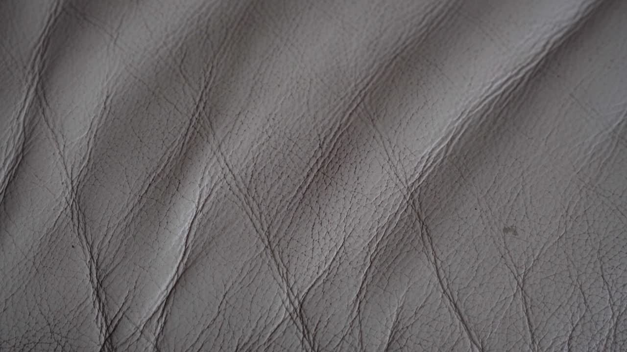A white and dirty leather sofa. Old leather sofa. Wrinkles in the leather of the sofa