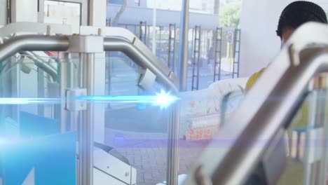 animation of blue light beam over african american woman walking through barrier at train station