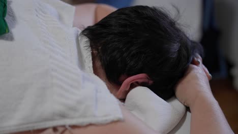 woman lying face down on massage table with hands resting in calm position