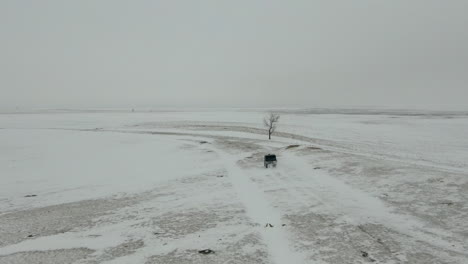 Toma-Aérea-Siguiente-Utv-Lado-A-Lado-Conduciendo-A-Través-De-Un-Campo-Nevado,-4k