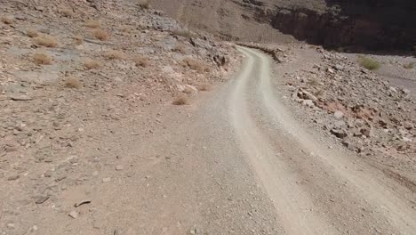 point of view of the driver overtaking an old pickup truck on a desertic mountain dirt road