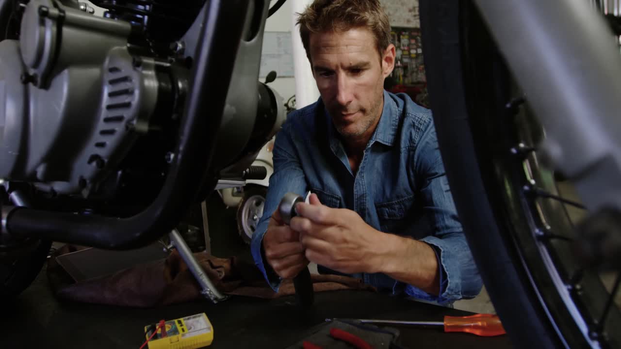 mecánico masculino reparando motocicletas en el garaje de reparación 4k