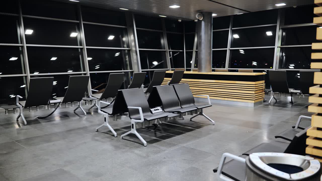 Wide shot of empty airport terminal at night with dark glass calm mood