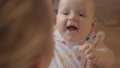 Mother-playing-with-her-newborn-giggling-daughter