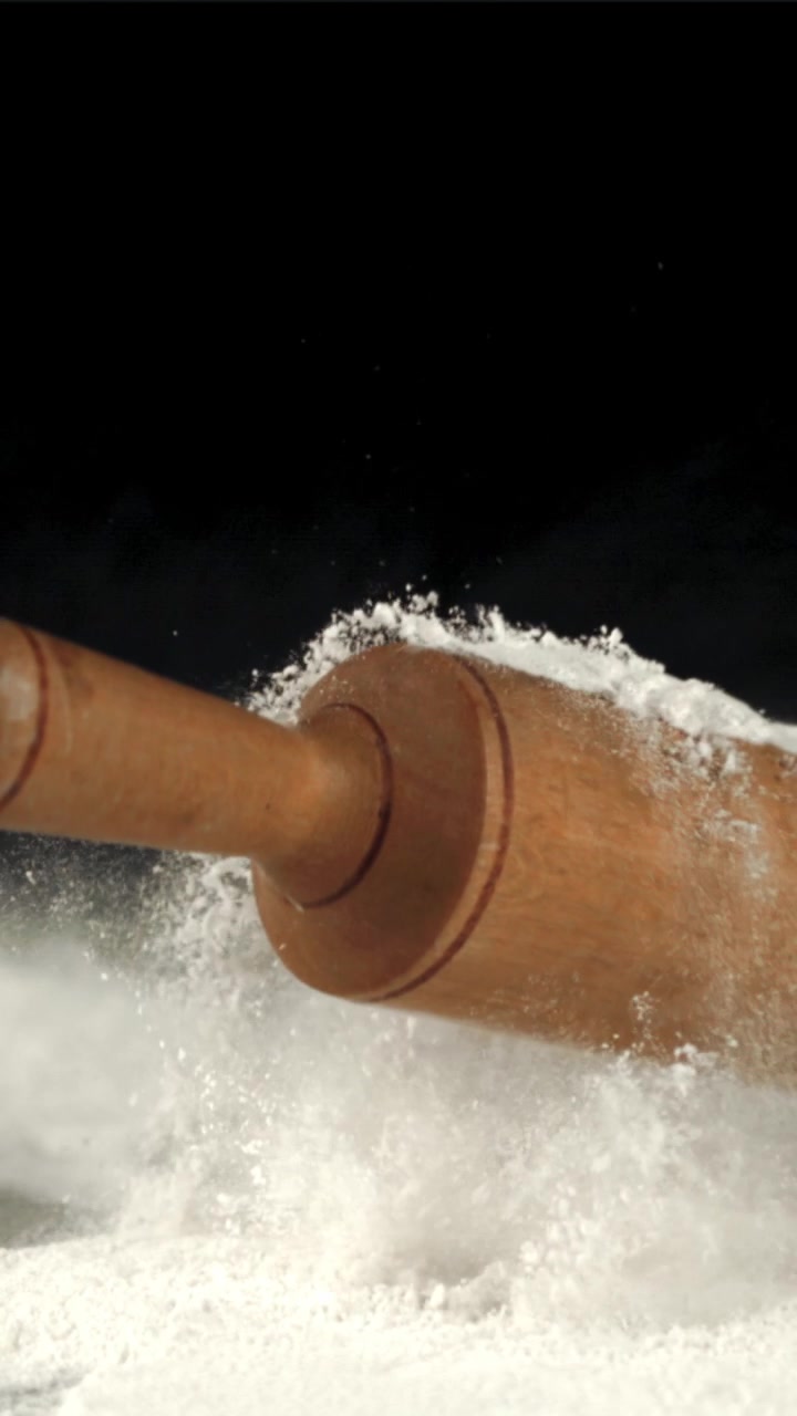 Mattarello di legno che cade al rallentatore nella farina