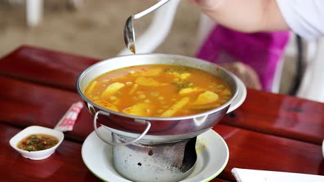 person serving yellow curry at a table