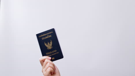 woman's hand shows the thailand passport ready for travel in white studio background with copy space