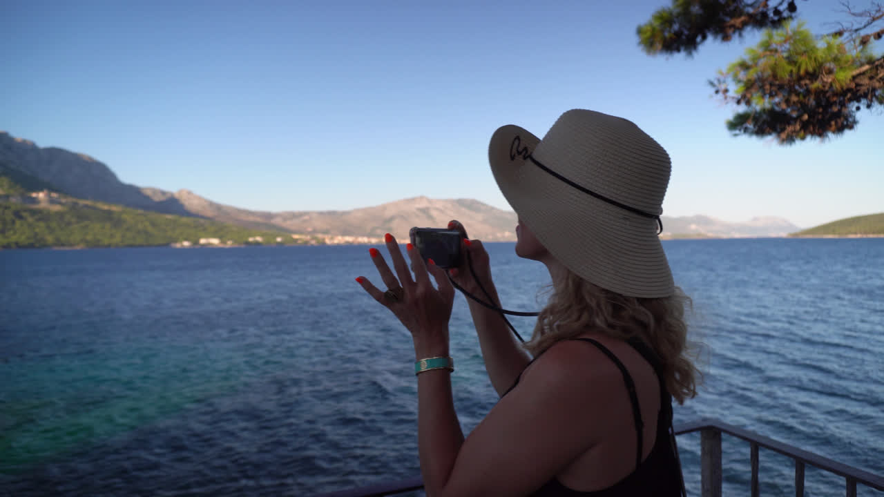 turista femenina tomando fotos de una majestuosa cadena montañosa rodeada de aguas turquesas de la isla
