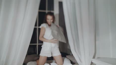 woman playing with a pillow in a bedroom at night