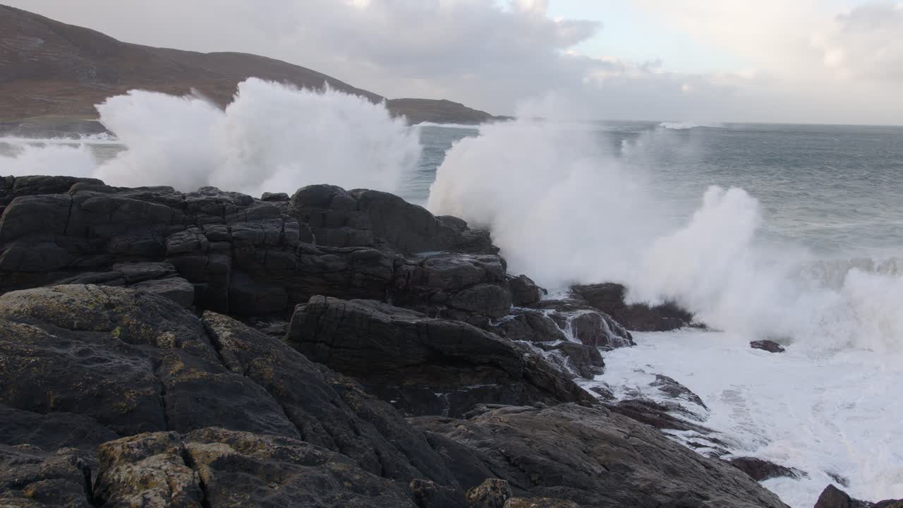 disparo en cámara lenta de grandes cepillos de olas blancas rompiendo sobre las rocas durante una tormenta en la bahía de tangasdale beach, cerca de castlebay en la isla de barra