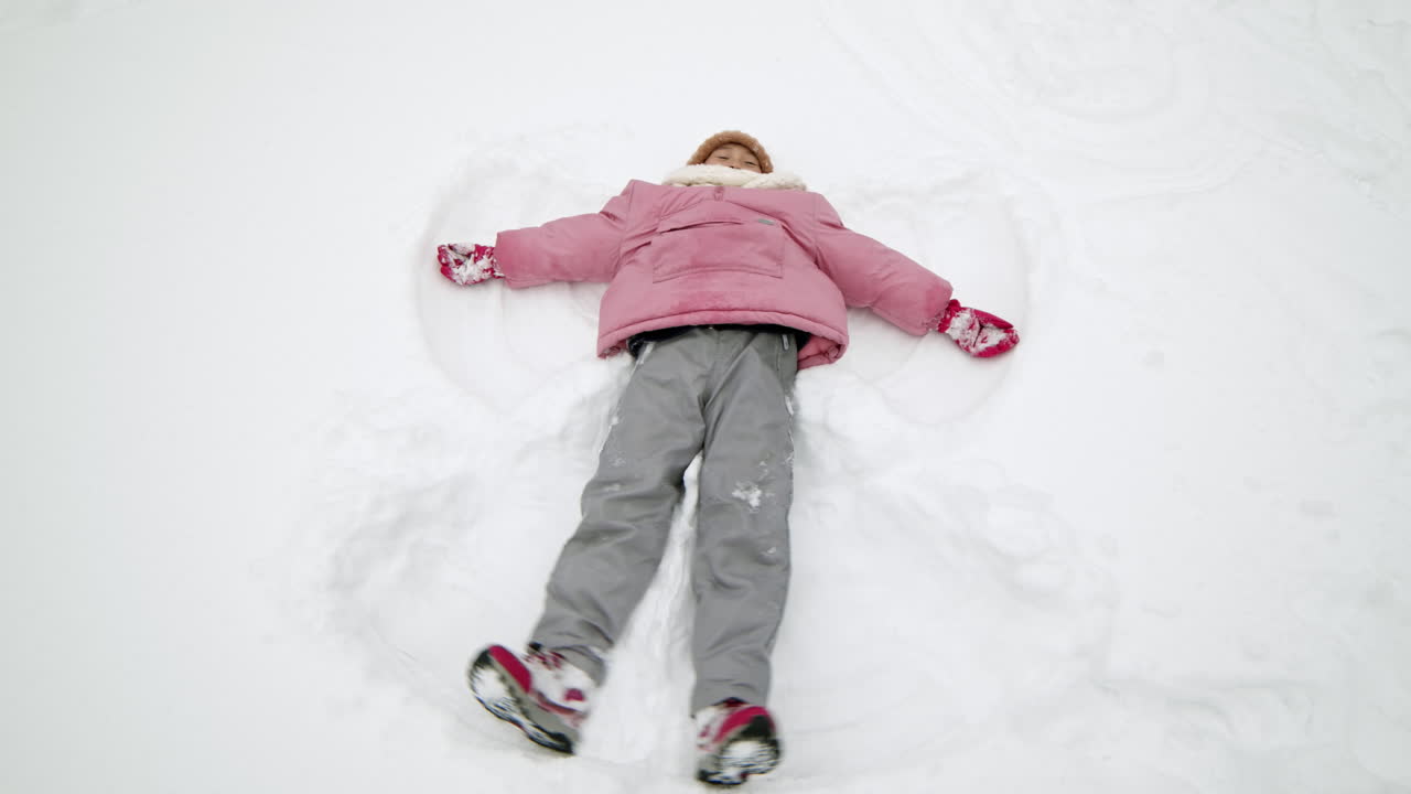 chica haciendo un ángel de nieve