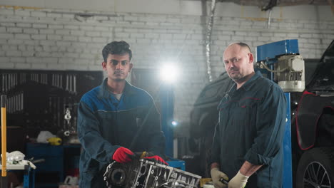 professionals in blue uniform stand near car engine in automotive workshop, illuminated by bright light, background features tools, equipment and mechanical components