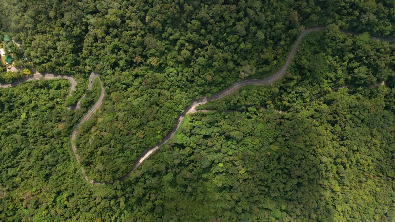imágenes aéreas de la carretera rodeada de selva tropical y nubosidad