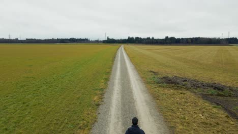 a lonely man is walking on a dirt road