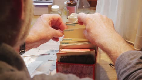 Old-caucasian-hands-sorting-through-different-pieces-of-leaf-gold