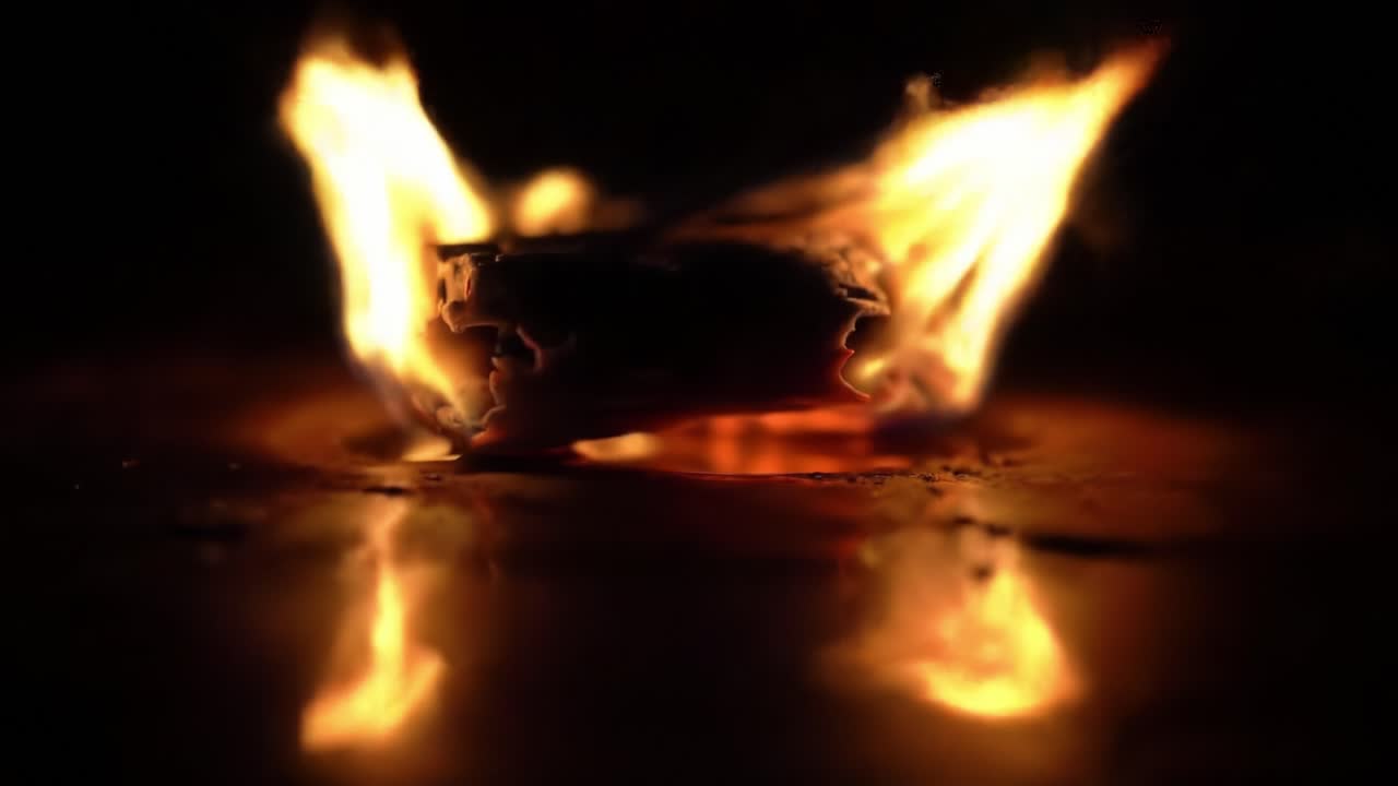 Captivating Flames: A Close-Up Exploration of the Dancing Fire and Its Reflective Surface, Showcasing the Intensity of Combustion and Light in an Enigmatic Setting