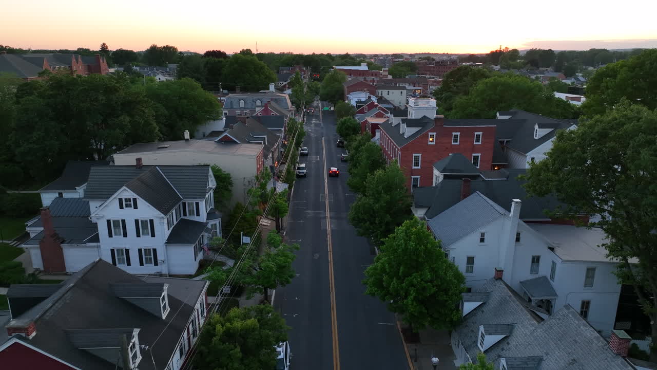 Ripresa aerea con dolly inverso di una strada di una piccola città americana con un'auto in transito.