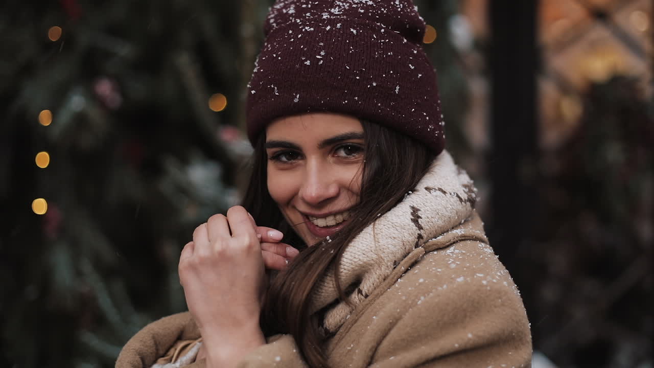 Woman in winter attire smiling in front of a Christmas tree