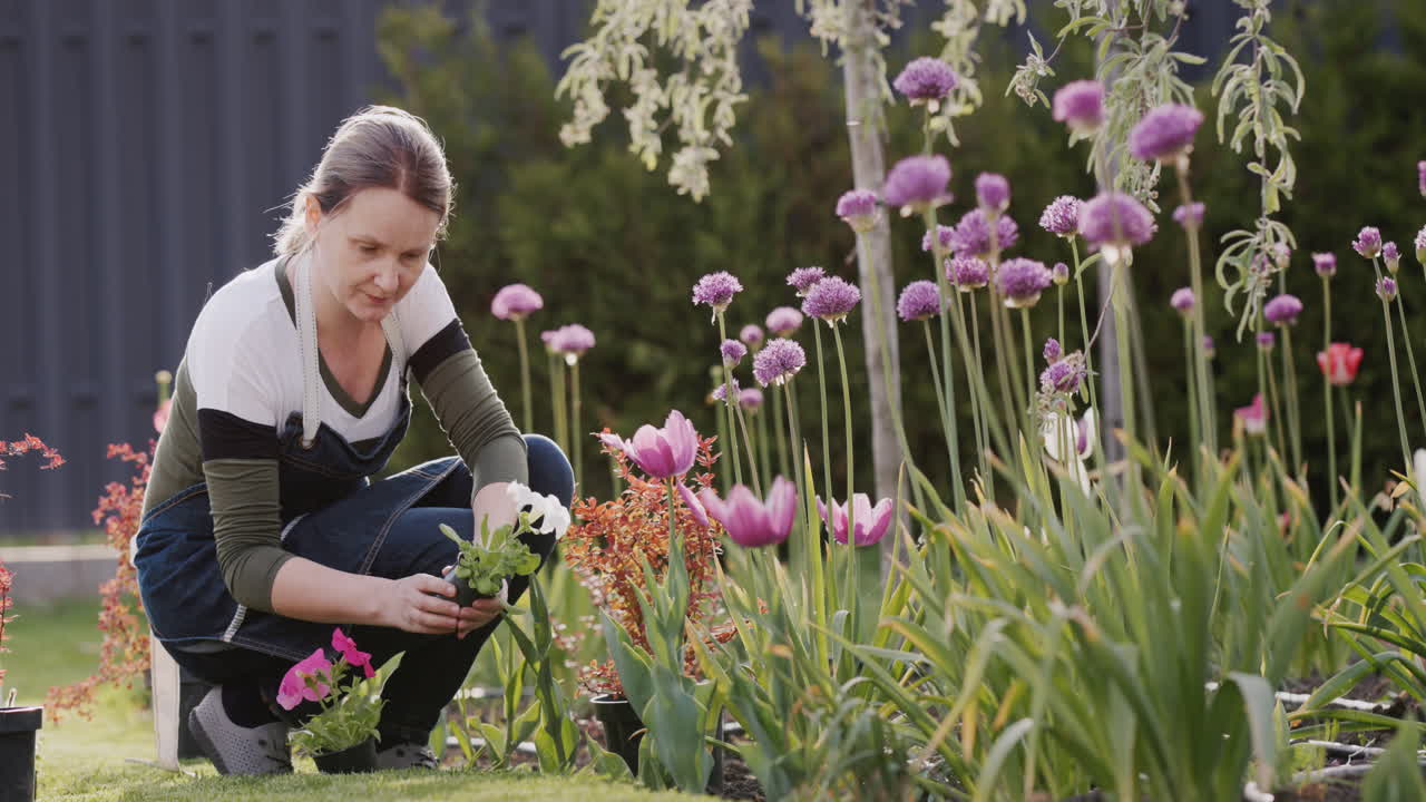 Uma jovem está plantando flores no quintal da casa.