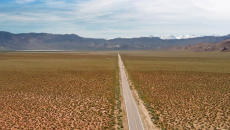 warped hyper lapse of clouds over long desert road with snowy mountains