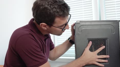 close up view of a concentrated computer service worker in glasses finishing upgrading computer hardware. support team. computer