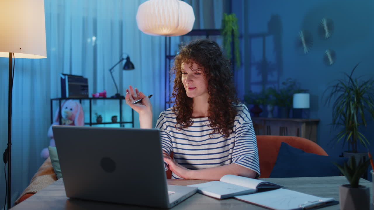 una joven profesora estudia en casa en una computadora portátil haciendo una videoconferencia hablando con una cámara web