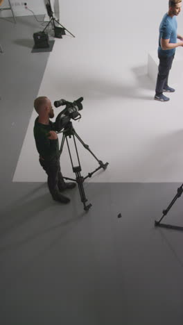 vertical video overhead shot of actors rehearsing movie or video scene in studio with film camera and sound crew 1