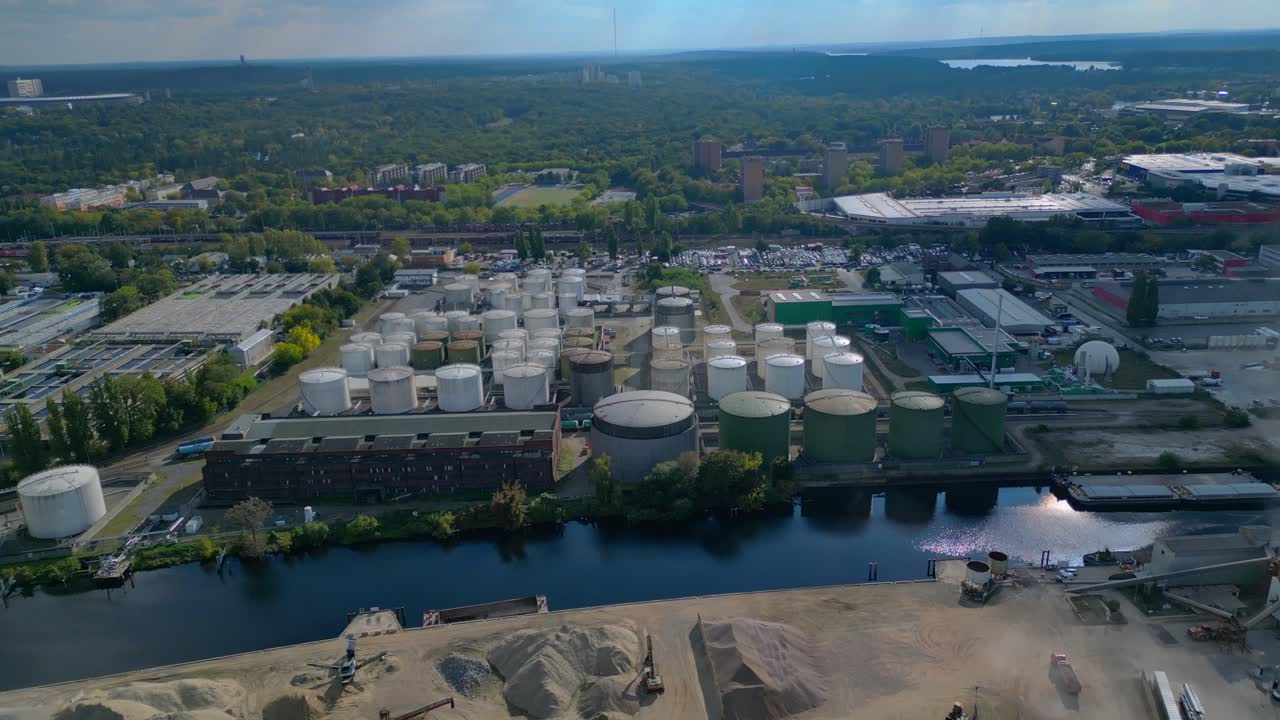 Berlin biogas plant with storage tanks by Spree river, producing renewable energy. Great aerial view flight fly push forward drone