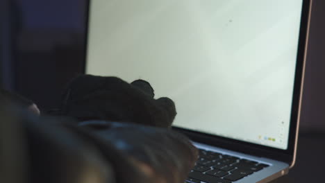 Hands-of-thief-typing-and-searching-on-computer-in-dark-room