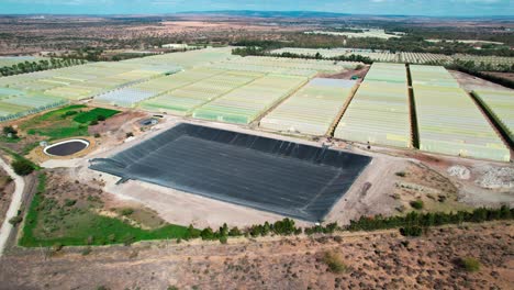 vista aérea de invernaderos en el campo de la granja con cuenca vacía para el suministro de agua
