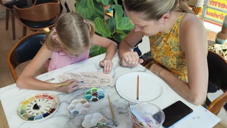 mother and daughter painting pottery