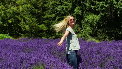 una mujer rubia feliz girando en un campo de lavanda púrpura en nueva zelanda