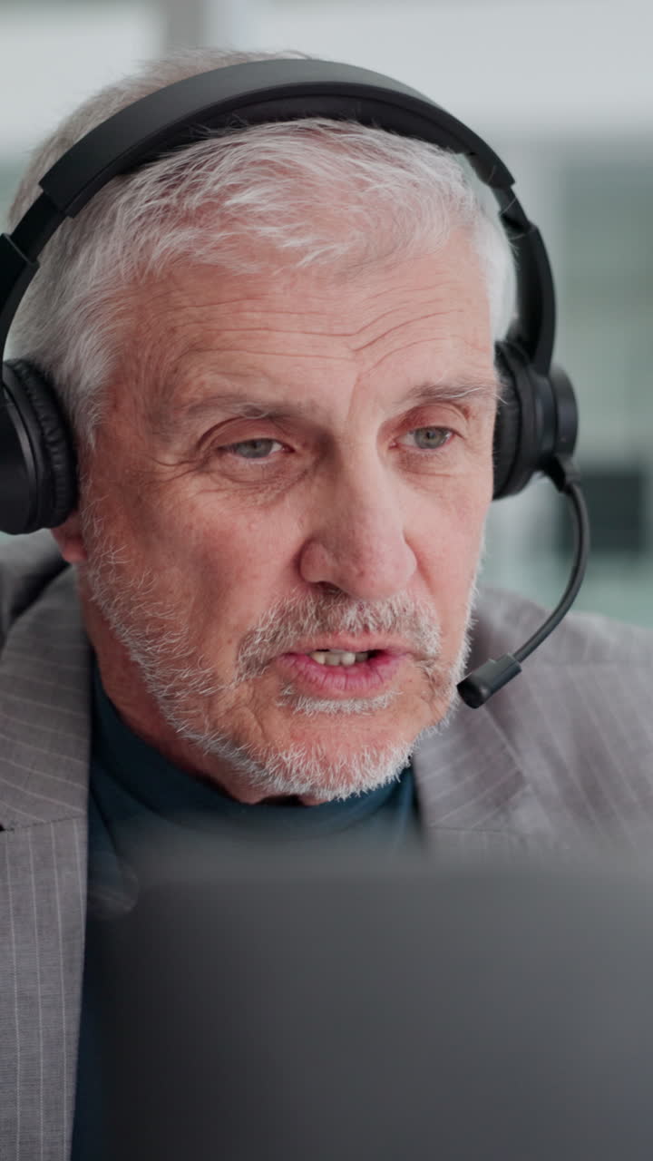 Ældre mand med headset taler i videoopkald fra bærbar computer