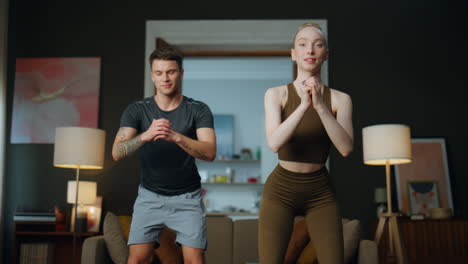 pair fitness training home. couple doing squats practicing gymnastic exercises.