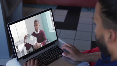 african american man having a video call with male office colleague on laptop at home