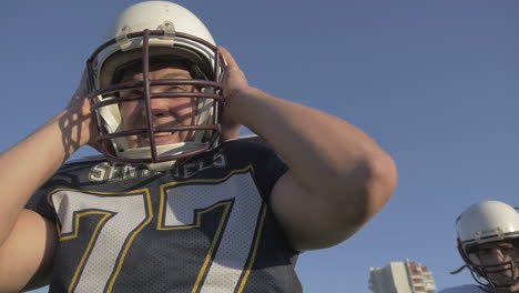 football player putting on helmet