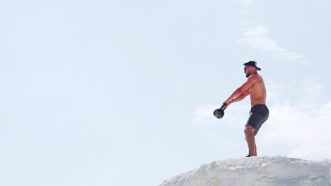 strong man doing exercises with a kettlebell while holding her hands. training in nature. slow motion