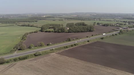 drone aerial view above british a580 east lancs highway in rural agricultural countryside wide orbit right
