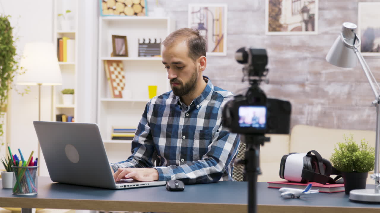 Man working on laptop in home studio with camera