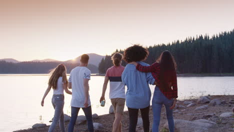 friends walking by the lake at sunset