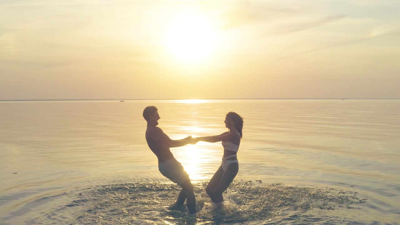 남자와 여자가 손을 잡고 아름다운 일몰을 향해 회전합니다.