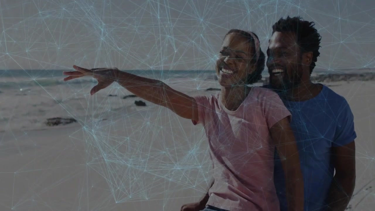 Woman lifting right arm on sandy beach initiating mesh overlay technology demo while man supporting