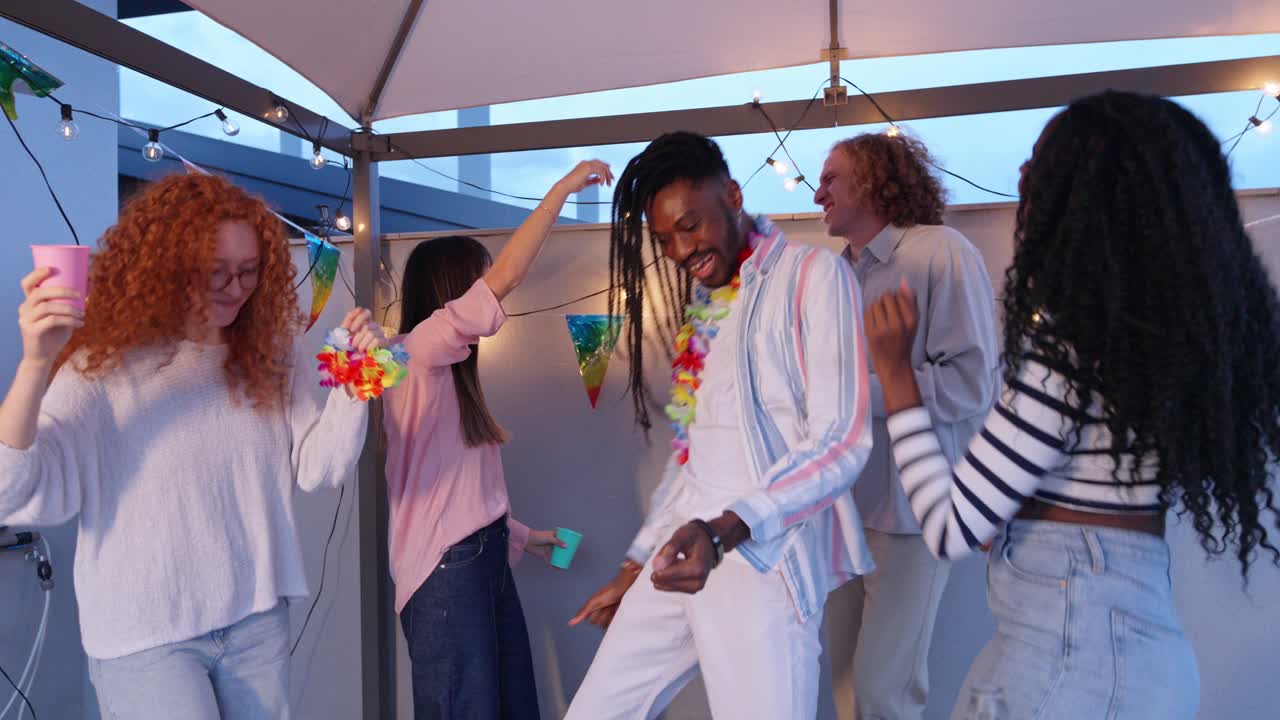 Group of friends celebrating and dancing at a rooftop party