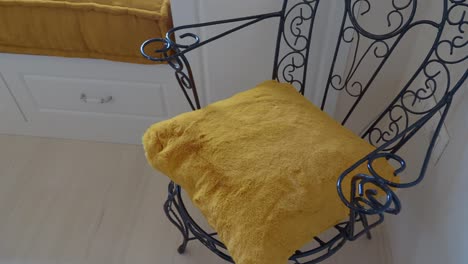 wrought iron chair with mustard yellow pillow