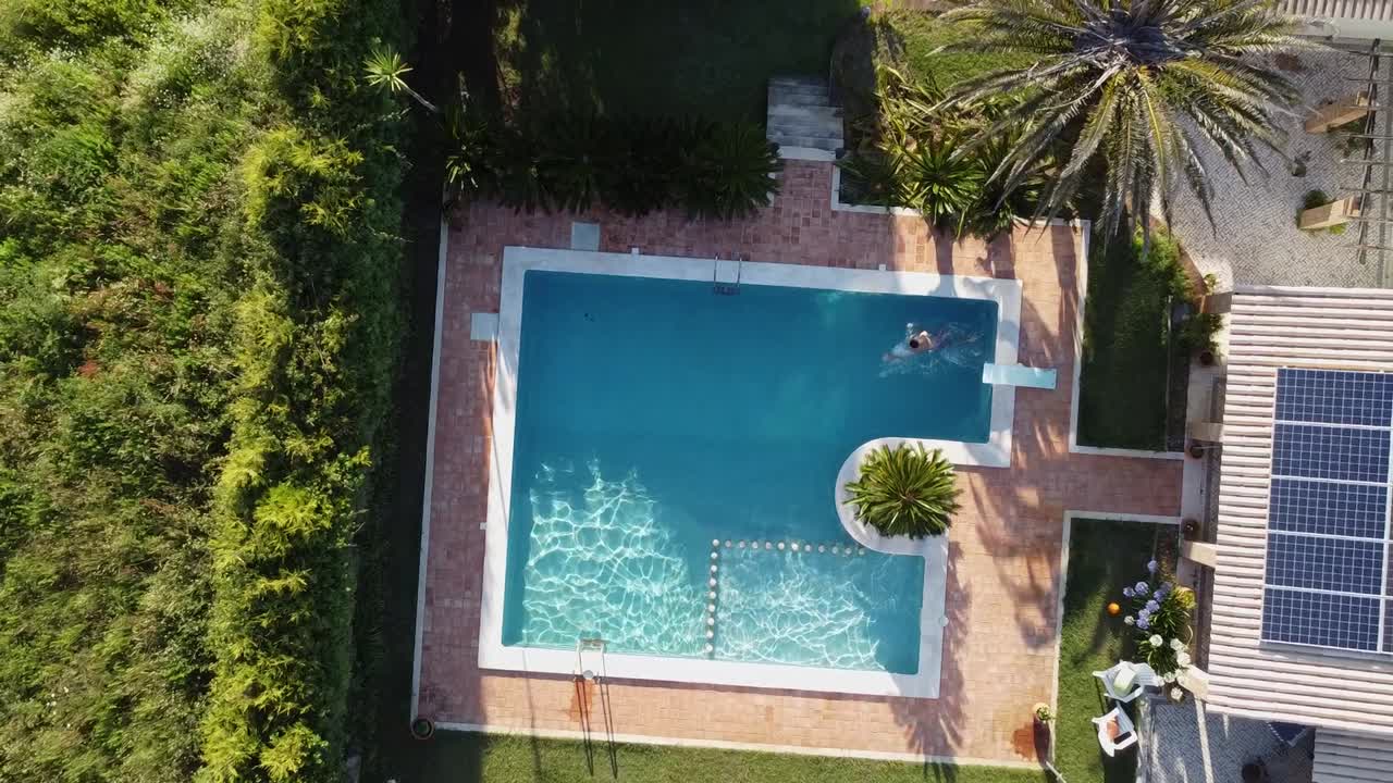 Mand svømmer i luksuriøs swimmingpool: Luftfoto i fugleperspektiv.