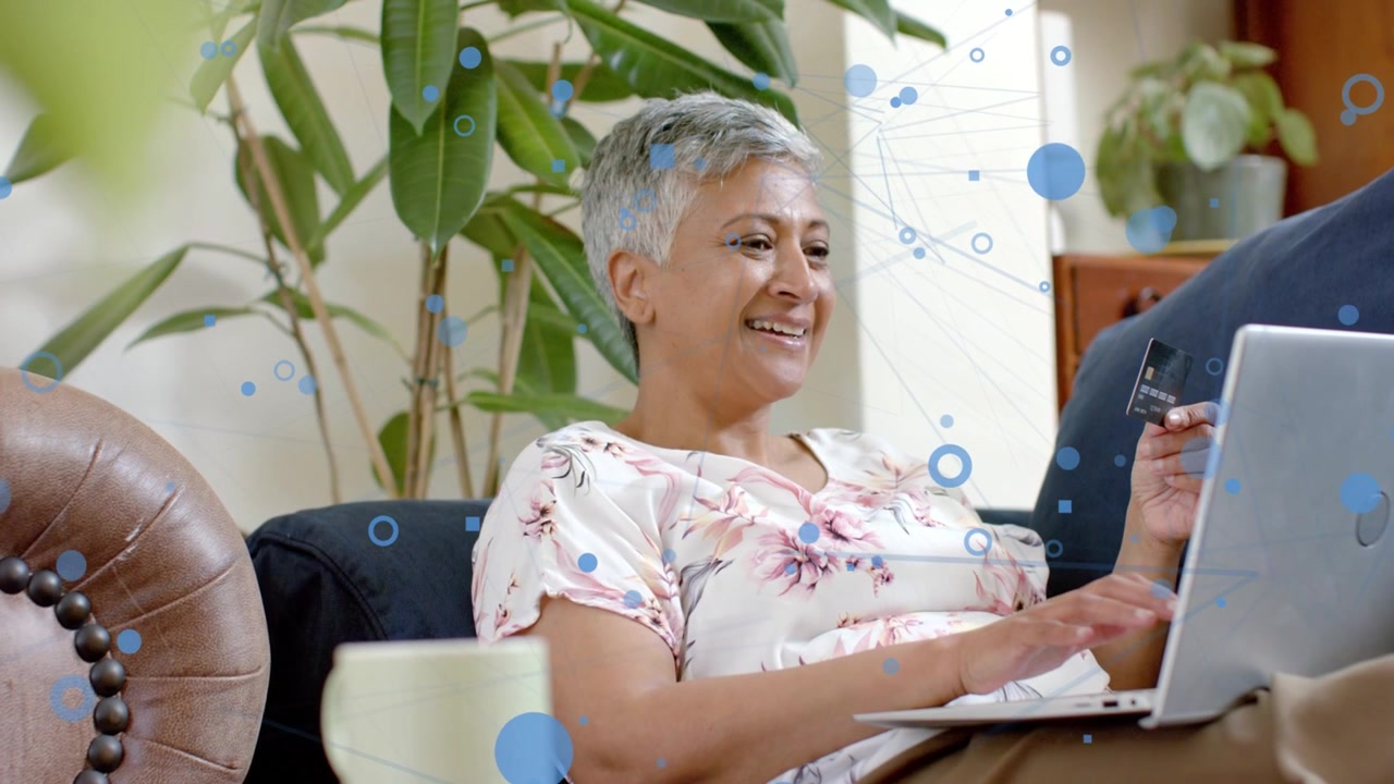 Woman typing card details on laptop while blue circles growing, completing online finance payment